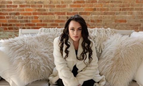 Mindy Smith sits on a plush white couch and smiles for the camera. 