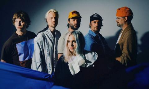 Members of the band The Head and the Heart pose in front of a grey background. 