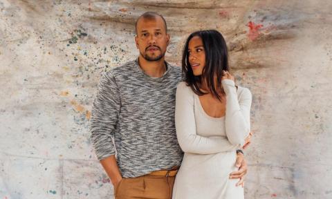 The duo from the band Johnnyswim pose in front of a textured wall. 