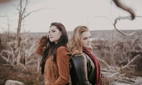 Cassie and Maggie pose in brown and black apparel. 