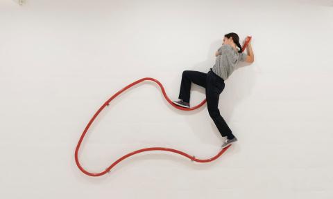 Artist, Laia Estruch, climbing on a minimalist exhibit.