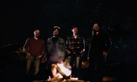 Tophouse stands near a burning fire-it and smiles for the camera. 