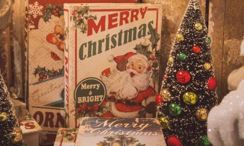 A Christmas Tree and an image of Santa on a box is positioned in front of a wooden background. 