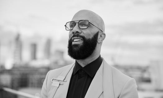 Common, outside in front of a cityscape in black and white