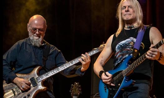 Bandmates from Dixie Dregs perform on stage with their guitars. 