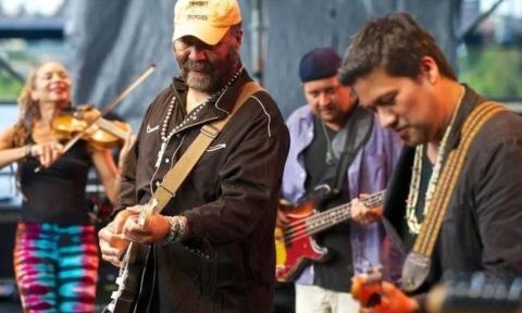 Bandmembers from Indigenous play their guitars on stage. 