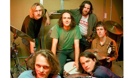 Bandmates from King Gizzard and the Wizard Lizard pose with their musical instruments. 
