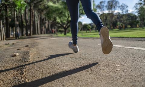 Legs of a runner casting a shadow on the side of an empty street