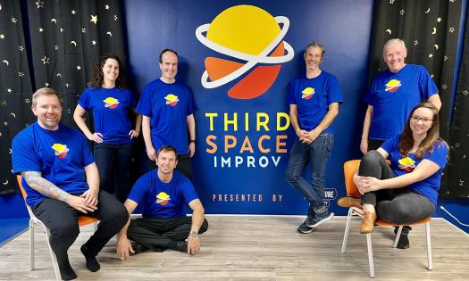 Improv performers in troupe t-shirts on stage at Third Space Improv