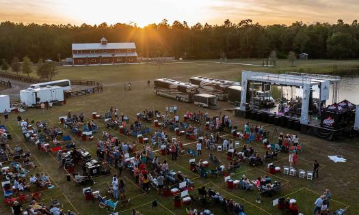 An aerial view of Concerts for a Cause, showing the outdoor venue, stage, barn, and sunset