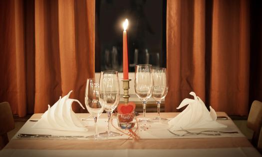 A table set for two, with one candle and two wine and water glasses
