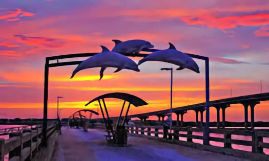 Sunset with hues of pink and purple and silhouetted dolphin sculptures leaping in the air