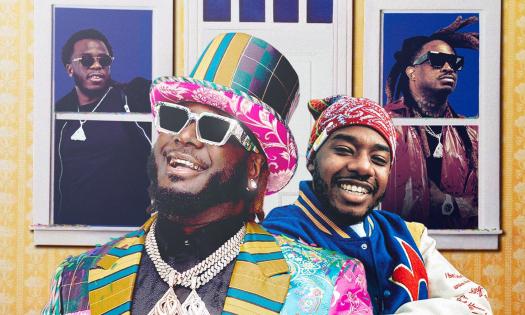 T-Pain smiles and poses in glasses and colorful clothing with a matching hat. 