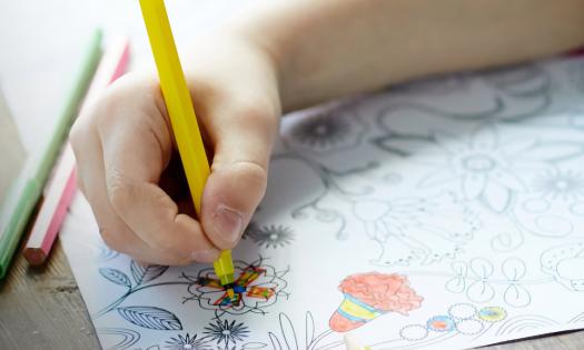 A child's hand coloring a picture