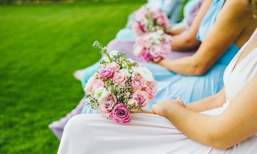 A view of four women sitting in chairs on a lawn, holding bouquets in their laps