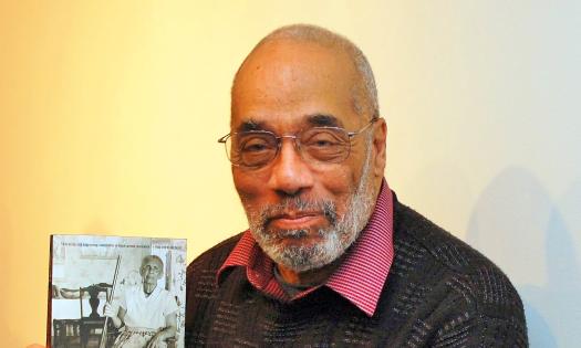 Black journalist, author and Civil Rights Activist Charlie Cobb holding a copy of his book