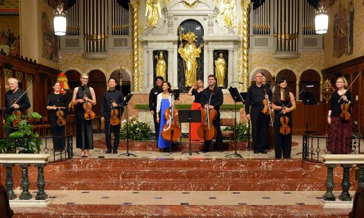 Members of a small string orchestra stand at the end of a concert in the Cathedral Basilica