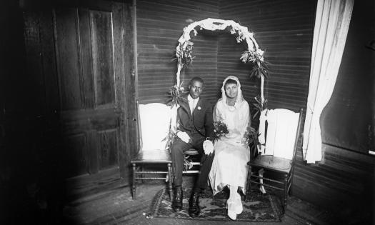 By Richard Twine, Eli and Teresa Bennett on their wedding day, seated on a decorated poarch swing