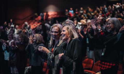 Two women standing an applauding in an audience at the St. Augustine Film Festival