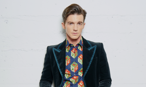 Drake Bell wears a blue blazer while posing in front of a white wall.