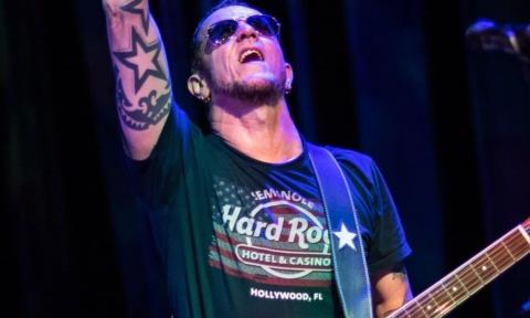 Gary Hoey wears black glasses while performing for audiences on stage.