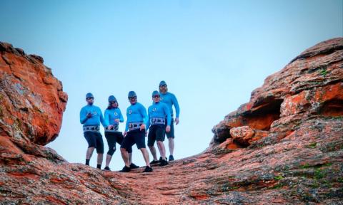 The Aquabats! strike a pose in their signature blue costumes while standing on top of a canyon.