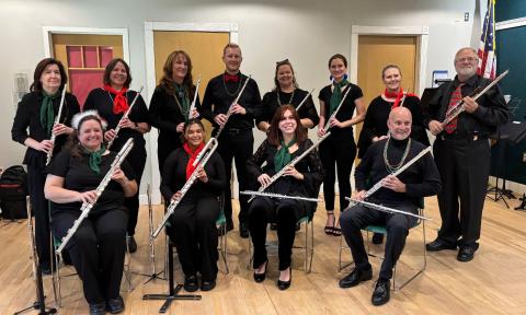 Twelve flutists, with their different types of flutes, seated 