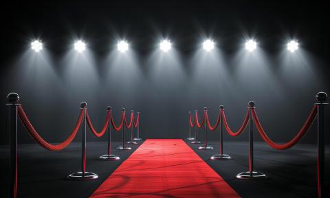 A red carpet, with velvet ropes on the side, under a row of spotlights