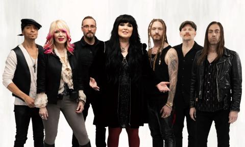 Bandmates from Heart wear black and pose in front of a white backdrop.