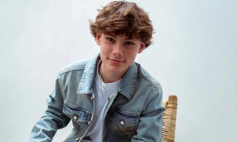 Maddox Batson wears a denim jacket and poses in front of a white backdrop.