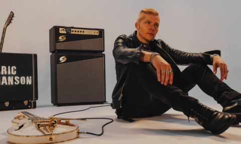 Eric Johanson wears black clothing and poses in front of a grey backdrop.
