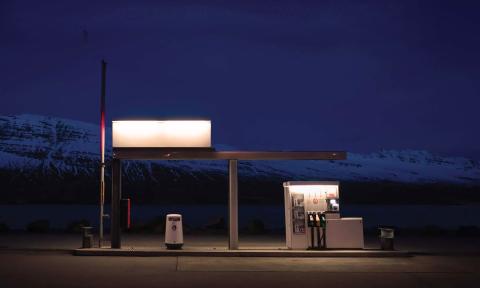 A gas station at night, with a lit pump and sign