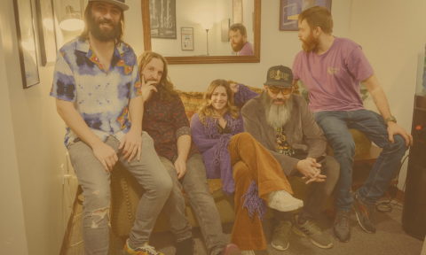 Bandmates from Bearly Dead smile and pose together in a cozy room with a mirror.