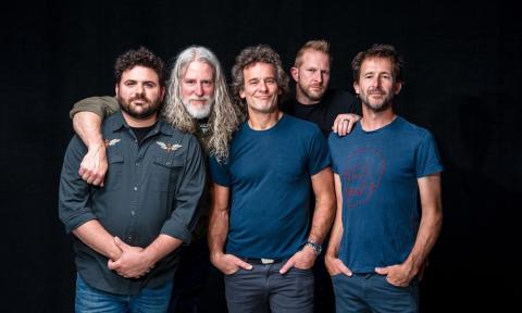 Bandmates from Carbon Leaf huddle together and pose in front of a black backdrop.