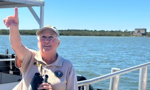 A volunteer naturalist points out a bird flying over Fort Matanzas National Monument