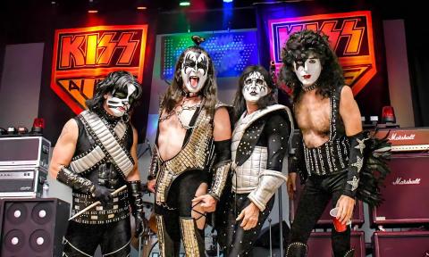 Members of Kiss Alive the Tribute standing next to gear on stage