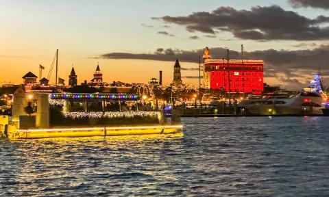 The brightly lit tour boat for Florida Water Tours cruising past the red-light-reflectingTreasury Building, 