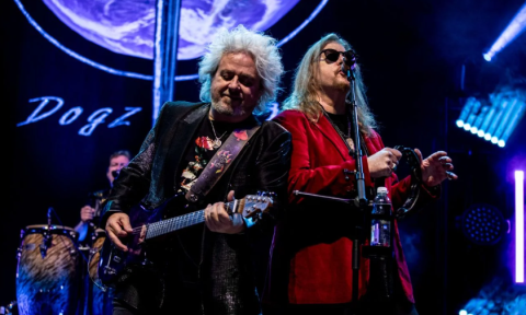 Bandmates from Toto smile and perform on stage.