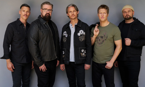 Bandmates from Home Free wear dark clothing and pose in front of a gray backdrop. 