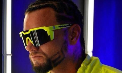 Riff Raff poses in yellow glasses and a matching shirt. 