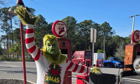 The Grinch on the grounds of the Classic Car Museum waving