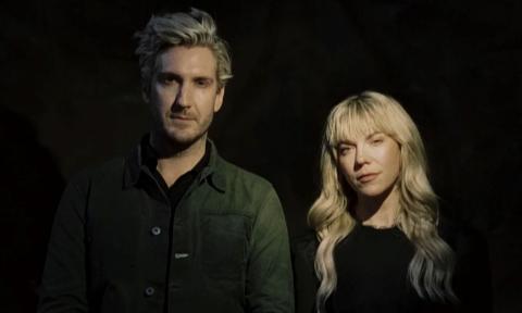 Bandmates from The Band Perry pose in black clothing in front of a black backdrop.