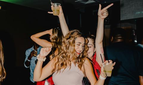 Two young women smile and dance at a party. 