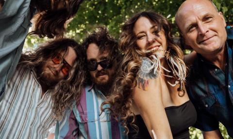 Bandmates from Magnolia Boulevard smile and huddle together.