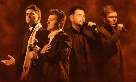 Bandmates from Celtic Thunder sing in front of a brown backdrop.
