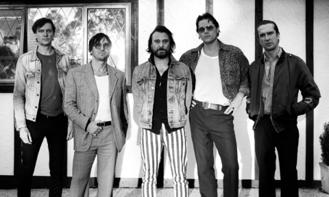 Bandmates from Jet pose in front of a wall with picture frames. 