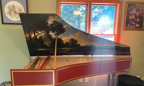 A harpsichord with the lid up and a beautifully painted interior
