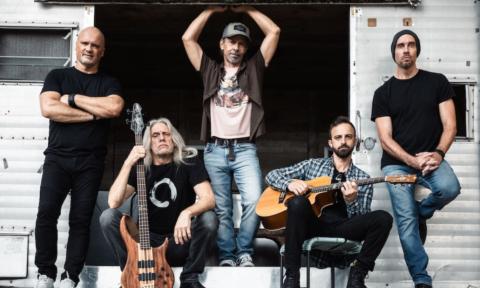 Bandmates from Given to Fly pose with their musical instruments.