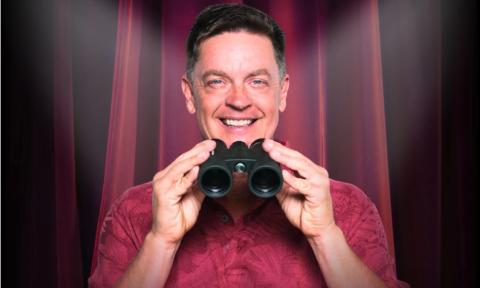 Jim Breuer smiles while clutching binoculars.