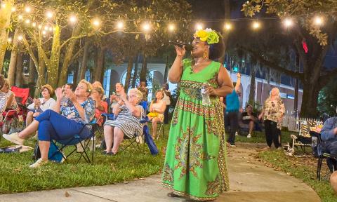 Singer Mama Blue, in a green dress performing outside under lantern lights